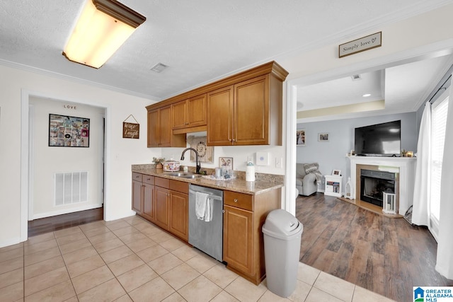 kitchen with ornamental molding, sink, dishwasher, and light hardwood / wood-style floors