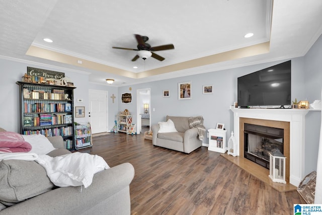 living room with ceiling fan, a raised ceiling, ornamental molding, and hardwood / wood-style flooring