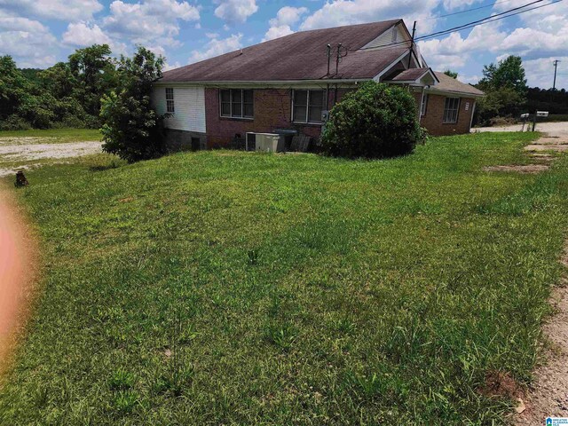 view of side of home with cooling unit and a lawn