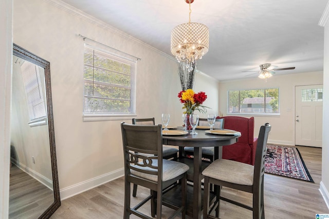 dining room featuring light hardwood / wood-style floors, ceiling fan with notable chandelier, and crown molding