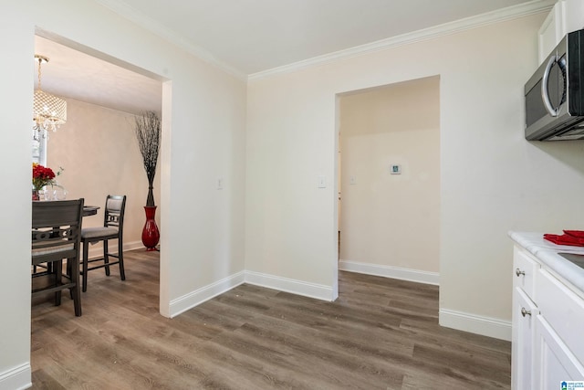 kitchen featuring white cabinetry, crown molding, wood-type flooring, and a chandelier