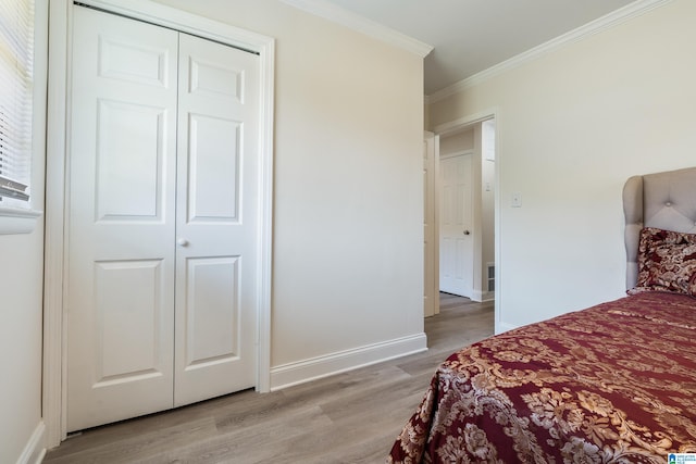 bedroom featuring light hardwood / wood-style flooring, ornamental molding, and a closet