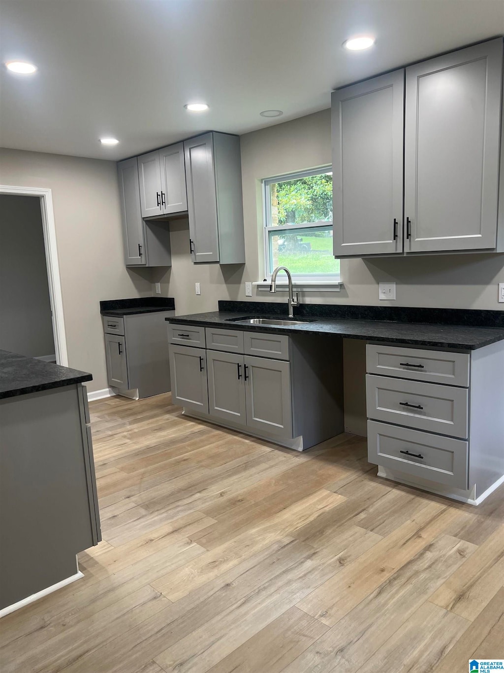 kitchen with gray cabinets, sink, and light wood-type flooring