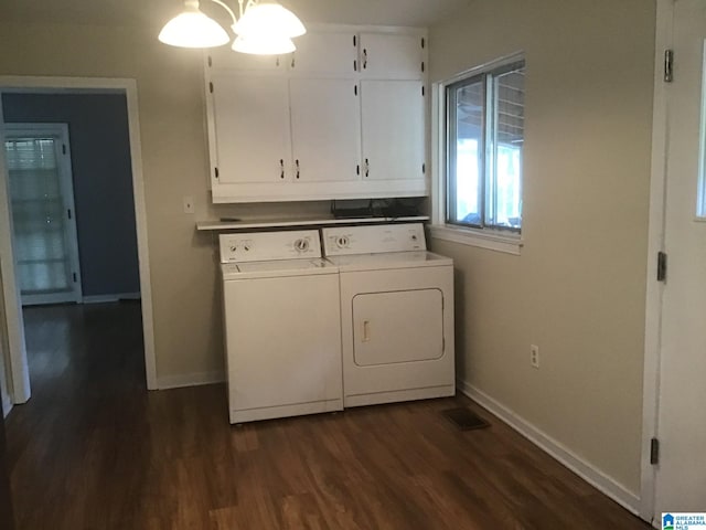 washroom featuring cabinets, washing machine and clothes dryer, and dark hardwood / wood-style flooring