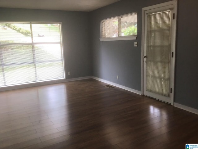 unfurnished room featuring dark hardwood / wood-style floors and a wealth of natural light