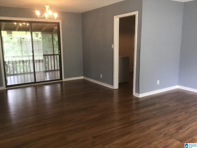 spare room featuring an inviting chandelier and dark wood-type flooring