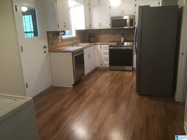 kitchen featuring appliances with stainless steel finishes, tasteful backsplash, white cabinetry, sink, and dark wood-type flooring