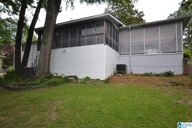 rear view of house with a sunroom, central AC unit, and a lawn