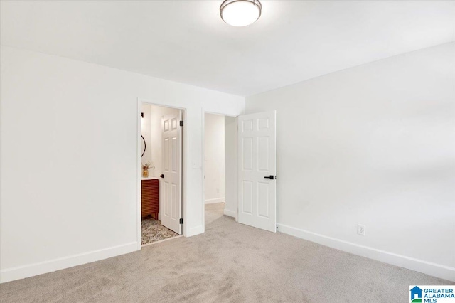 unfurnished bedroom featuring connected bathroom and light carpet