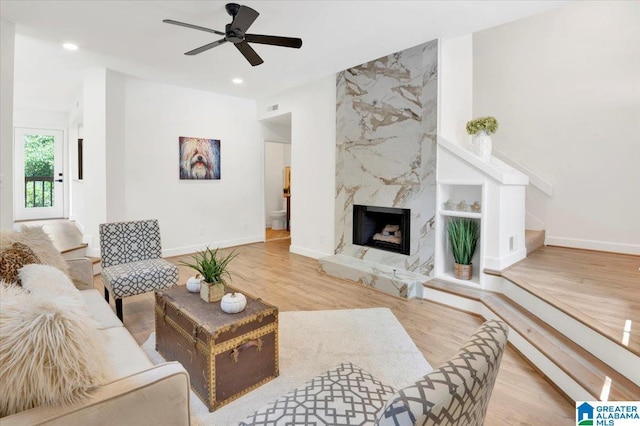 living room with light wood-type flooring, a fireplace, and ceiling fan