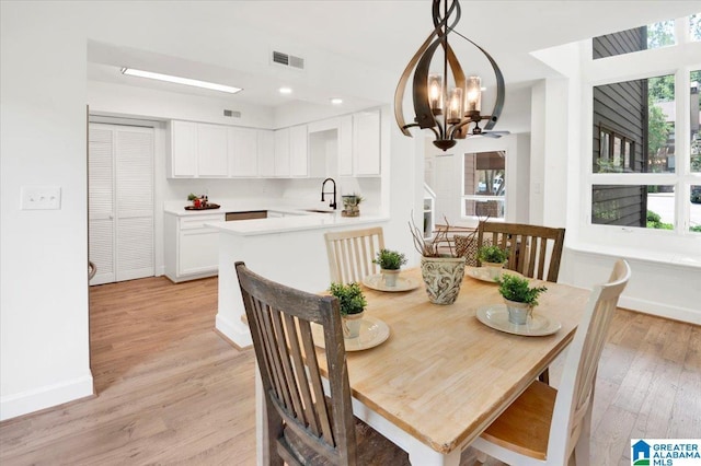 dining area featuring a notable chandelier, sink, and light hardwood / wood-style flooring