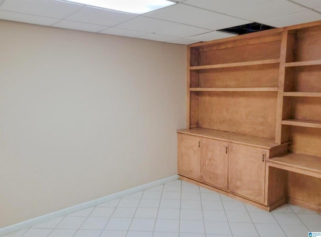 interior space featuring a paneled ceiling and light tile patterned floors