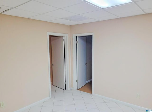 tiled empty room featuring a paneled ceiling