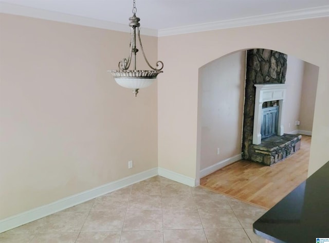 unfurnished dining area featuring a fireplace, light tile patterned floors, and crown molding