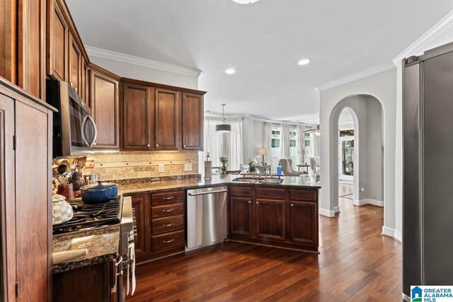 kitchen with dark stone counters, stainless steel appliances, tasteful backsplash, kitchen peninsula, and dark hardwood / wood-style flooring