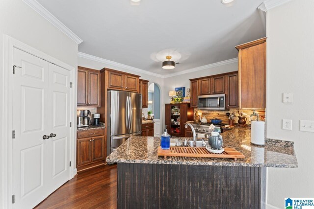 kitchen with stainless steel appliances, kitchen peninsula, and dark wood-type flooring