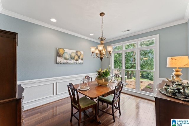 dining space with dark hardwood / wood-style floors, crown molding, and a chandelier