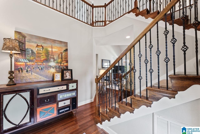 stairs with hardwood / wood-style flooring and a towering ceiling