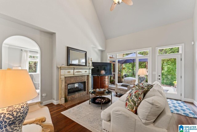 living room with a tile fireplace, high vaulted ceiling, dark wood-type flooring, and ceiling fan