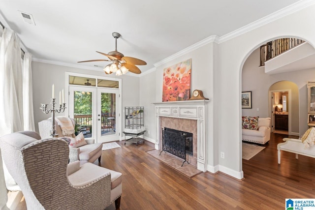 living room featuring french doors, ceiling fan, dark hardwood / wood-style floors, a fireplace, and ornamental molding