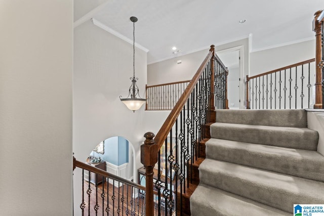 staircase featuring a high ceiling, crown molding, and hardwood / wood-style floors