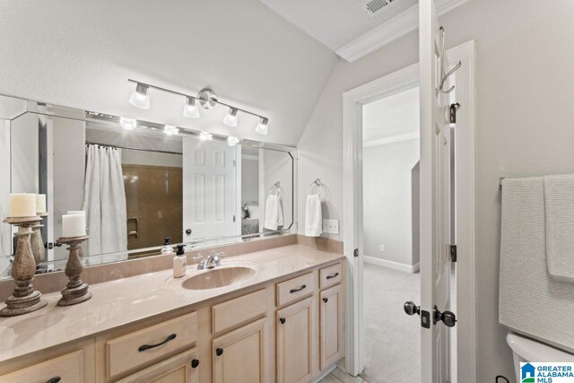 bathroom with lofted ceiling, vanity, and ornamental molding