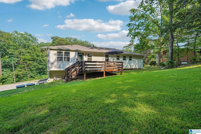 rear view of house featuring a wooden deck and a lawn