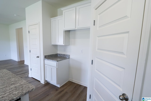 kitchen featuring dark hardwood / wood-style flooring, white cabinets, and dark stone counters