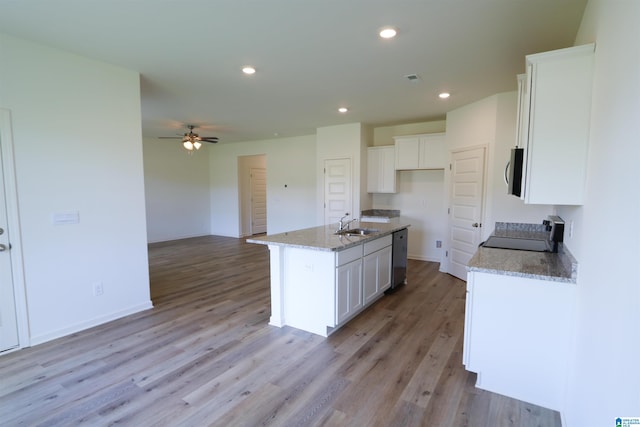 kitchen featuring white cabinetry, stainless steel appliances, light stone counters, light hardwood / wood-style flooring, and a center island with sink