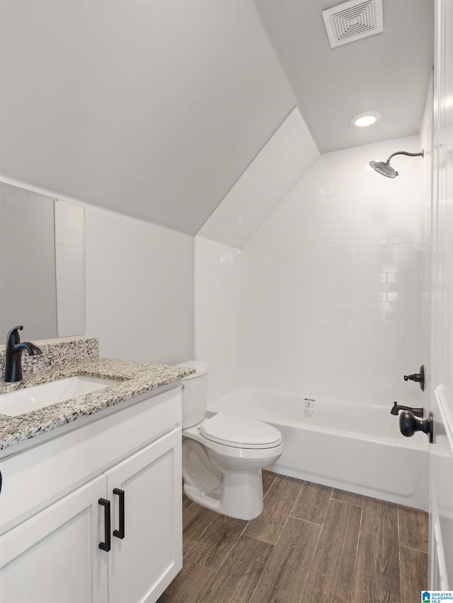 full bathroom with vanity, tiled shower / bath, hardwood / wood-style flooring, and toilet