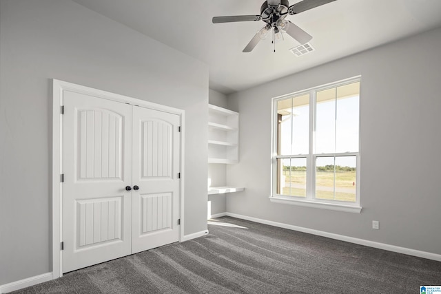 unfurnished bedroom with a closet, ceiling fan, and dark carpet