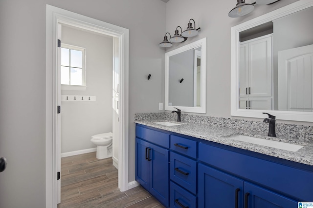 bathroom with hardwood / wood-style floors, toilet, and dual bowl vanity