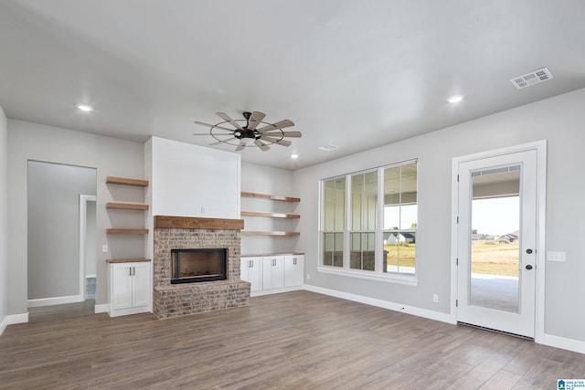 unfurnished living room with a brick fireplace, hardwood / wood-style flooring, and ceiling fan