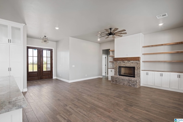 unfurnished living room featuring hardwood / wood-style flooring, french doors, a brick fireplace, and ceiling fan