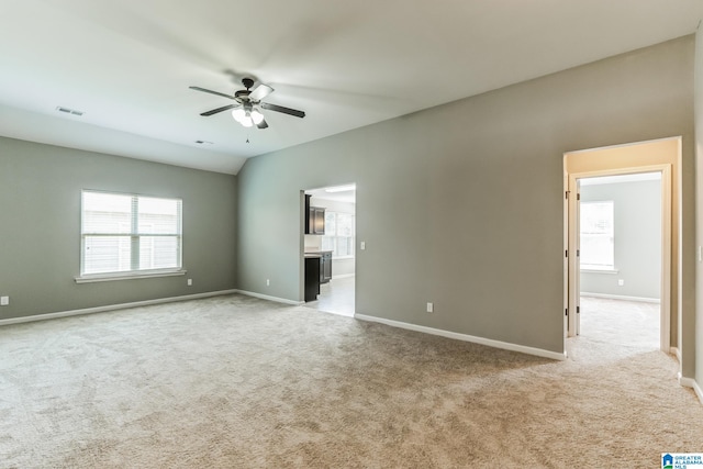 spare room featuring lofted ceiling, light colored carpet, and ceiling fan