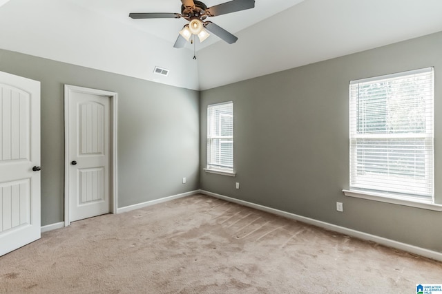 unfurnished bedroom featuring multiple windows, ceiling fan, vaulted ceiling, and light colored carpet