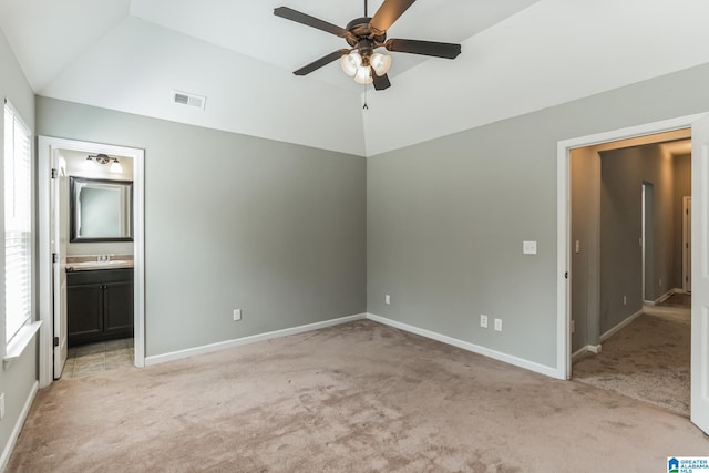 unfurnished bedroom with ceiling fan, sink, light carpet, vaulted ceiling, and ensuite bathroom