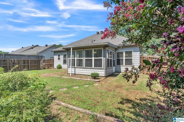 back of house with a sunroom and a lawn