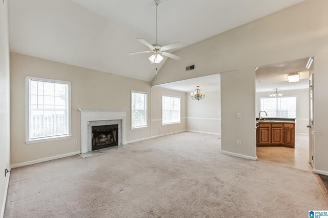 unfurnished living room featuring sink, a fireplace, light tile patterned floors, ceiling fan with notable chandelier, and high vaulted ceiling