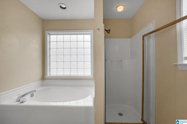 bathroom with shower with separate bathtub and plenty of natural light