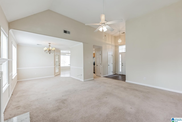 unfurnished living room with plenty of natural light, ceiling fan with notable chandelier, carpet floors, and high vaulted ceiling