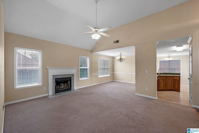 unfurnished living room with ceiling fan with notable chandelier, a premium fireplace, light tile patterned floors, and plenty of natural light