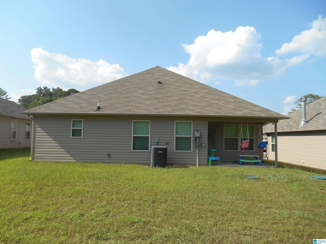 back of property with central AC unit and a lawn