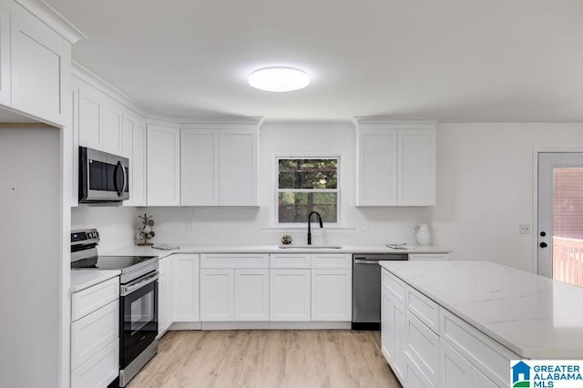 820 Boozer Rd, Heflin, AL 36264 - kitchen with stainless steel appliances, a sink, light wood finished floors, white cabinets, and light stone countertops
