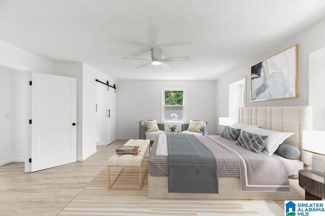 820 Boozer Rd, Heflin, AL 36264 - bedroom with wood finished floors, a barn door, a textured ceiling, a ceiling fan, and baseboards