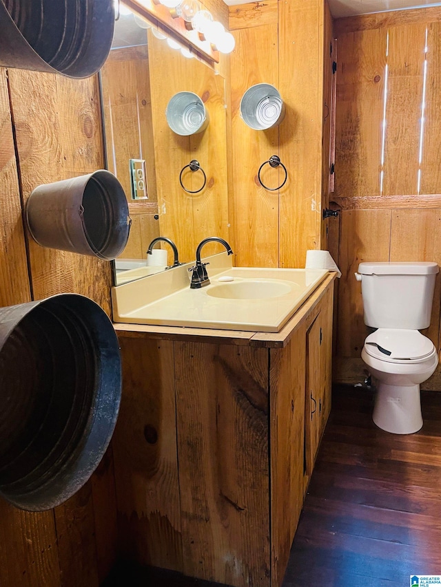 bathroom with wooden walls, toilet, vanity, and hardwood / wood-style flooring