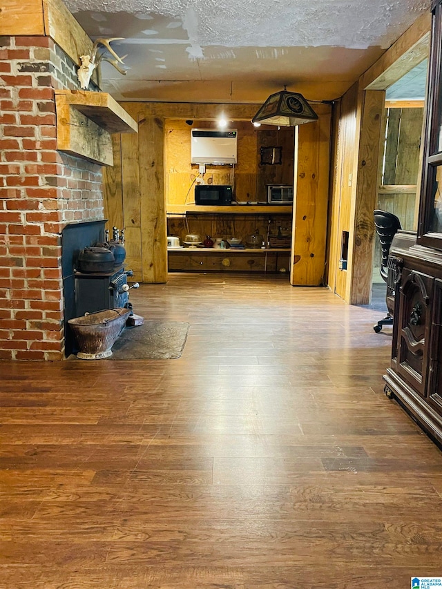 living room featuring hardwood / wood-style flooring, a wood stove, a textured ceiling, and wooden walls