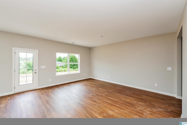 spare room featuring baseboards and wood finished floors