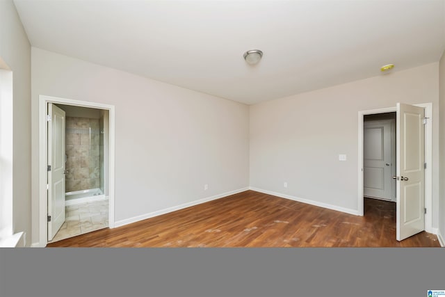 unfurnished bedroom featuring ensuite bathroom and wood-type flooring