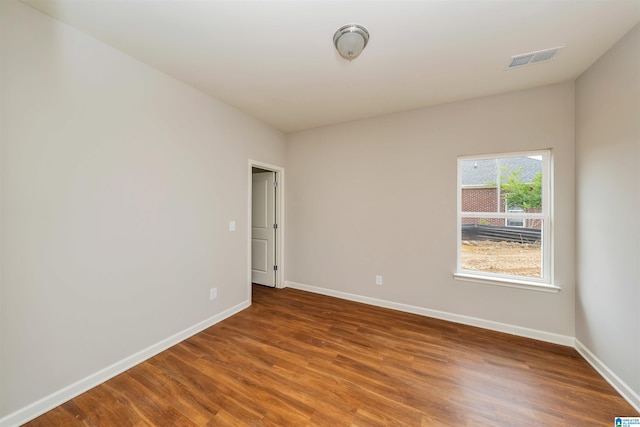 spare room with visible vents, baseboards, and wood finished floors